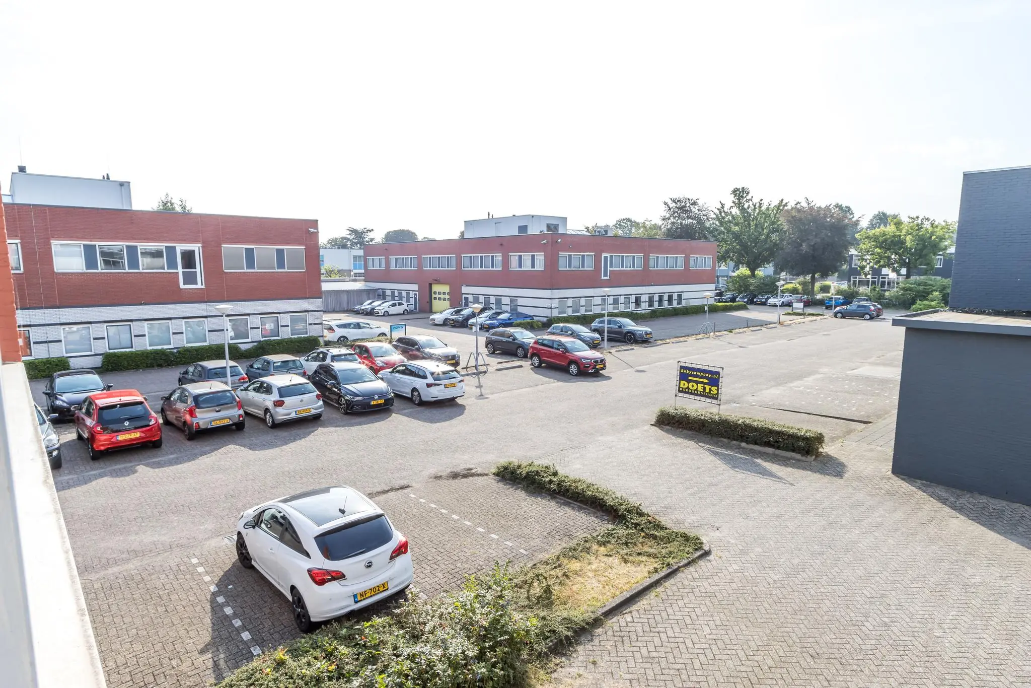 Bedrijventerrein aan de Jan van Eycklaan met geparkeerde auto's en een bedrijfspand met een bord van Doets.